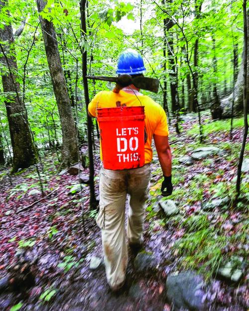 Conservation Corps crew member Eduardo Gil walking with a bucket. Photo by Eduardo Gil.