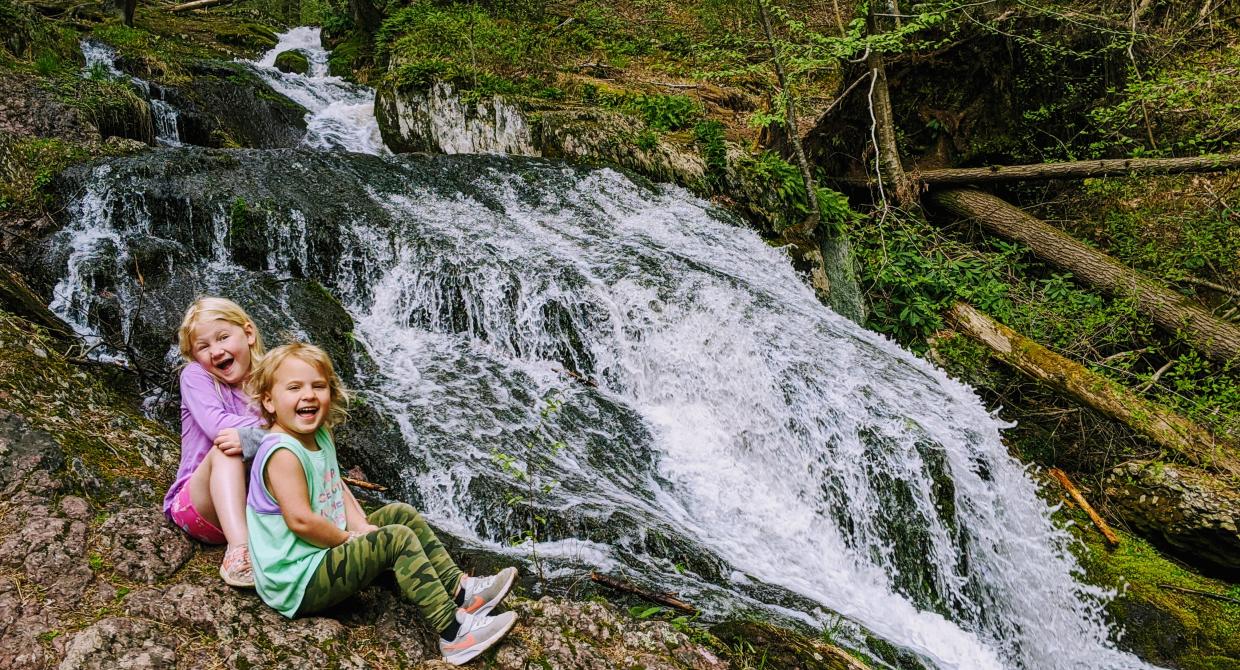 Young girls sitting near a waterfall. Photo by Asher Lov.