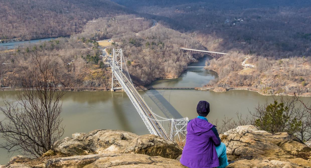 Hiker at Anthony's Nose overlooking Bear Mountain in winter. Photo by Adobe Stock.